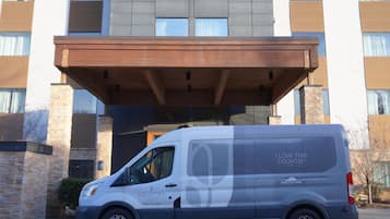 Un bâtiment Country Inn & Suites au design moderne, avec une entrée imposante et un fourgon garé devant.