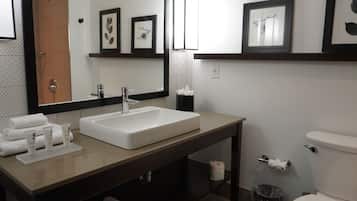 Une salle de bain moderne avec un grand lavabo, un miroir et une œuvre d’art encadrée accrochée au mur.