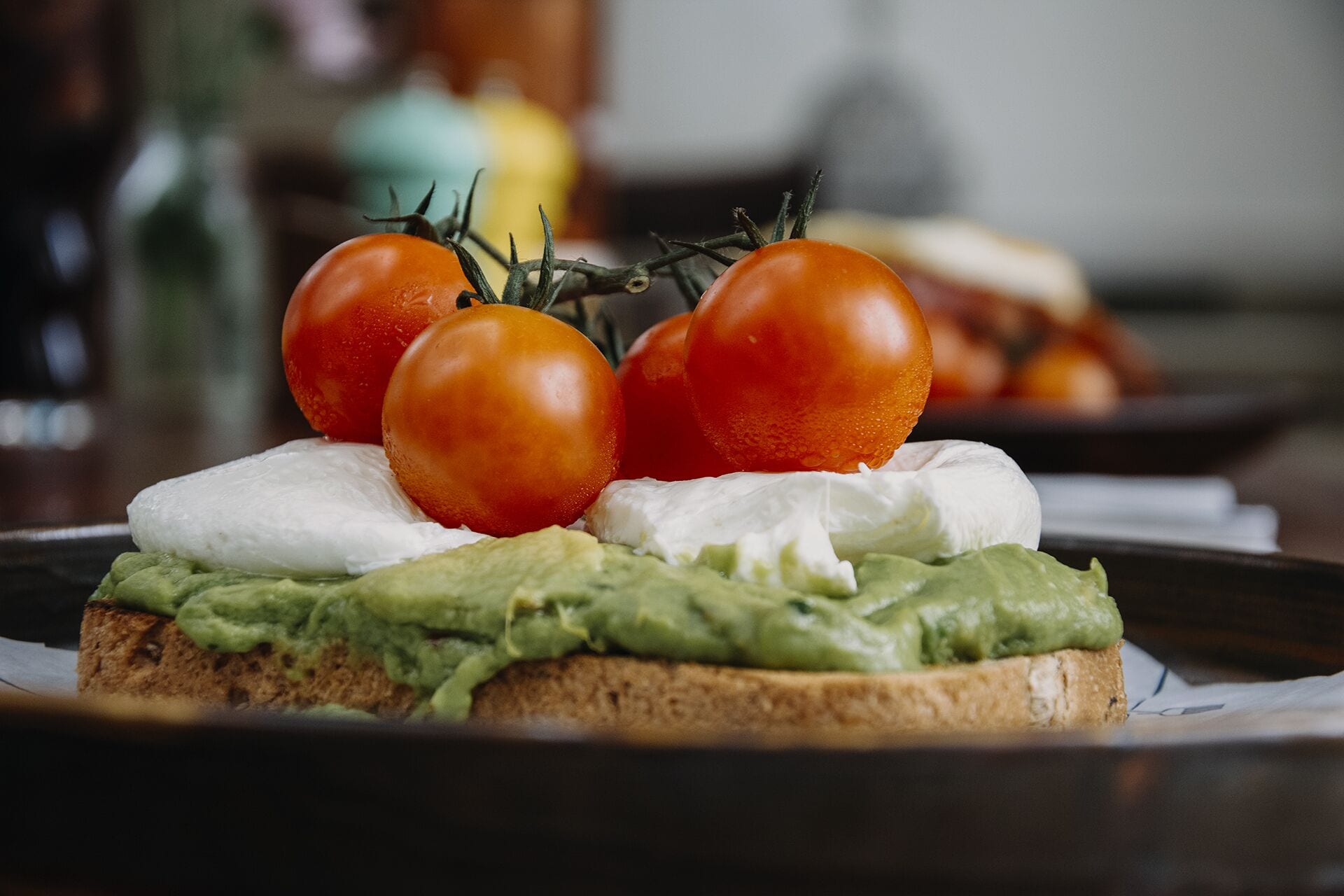 A sandwich with avocado, tomato, and cheese on a slice of bread.