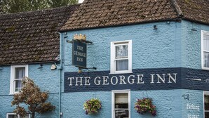 A building with a sign reading "The George Inn" and a crown emblem above the sign. - The George Inn (Warminster)