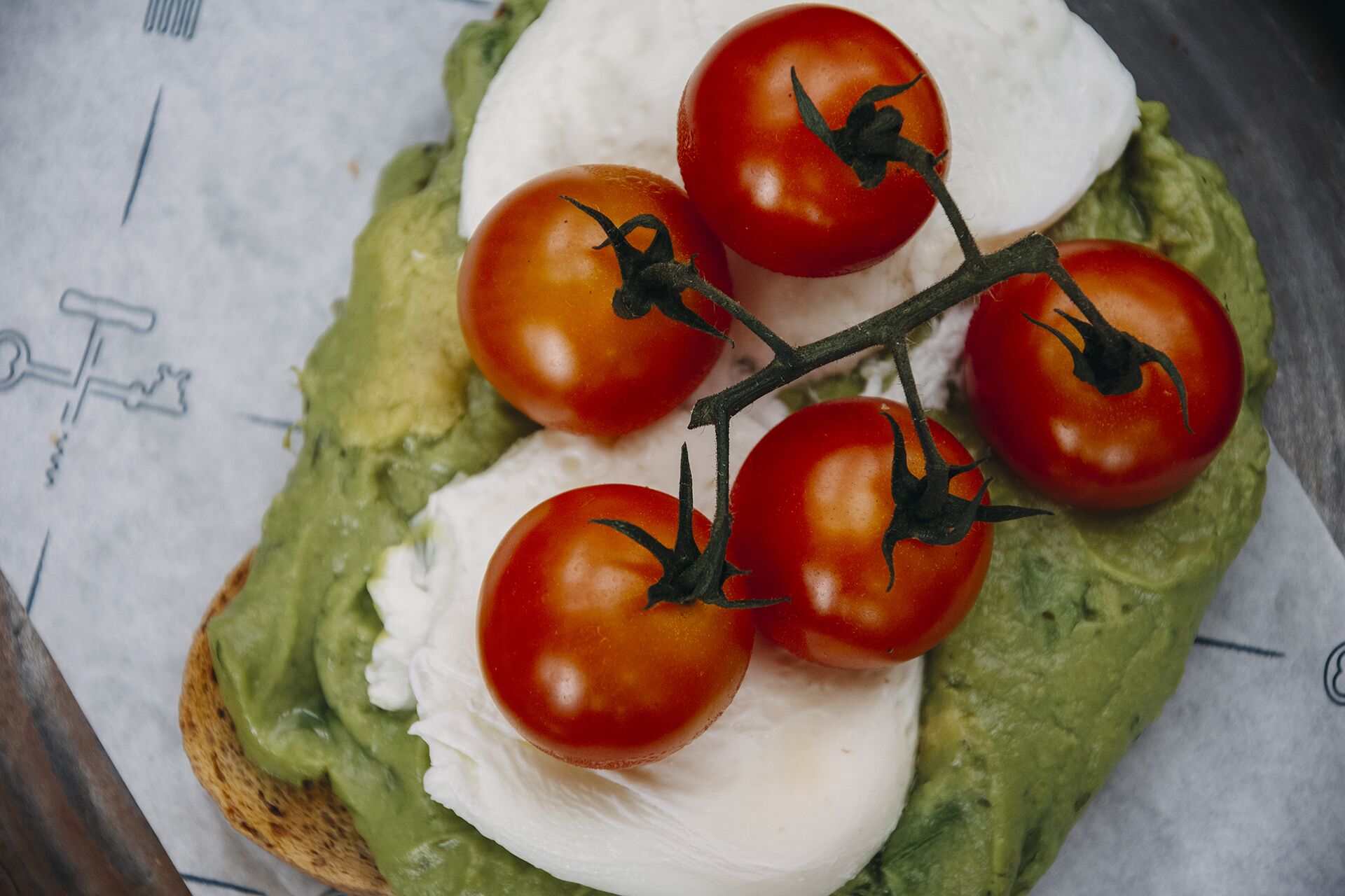 En sandwich med avocado, tomat og ost på et stykke brød.