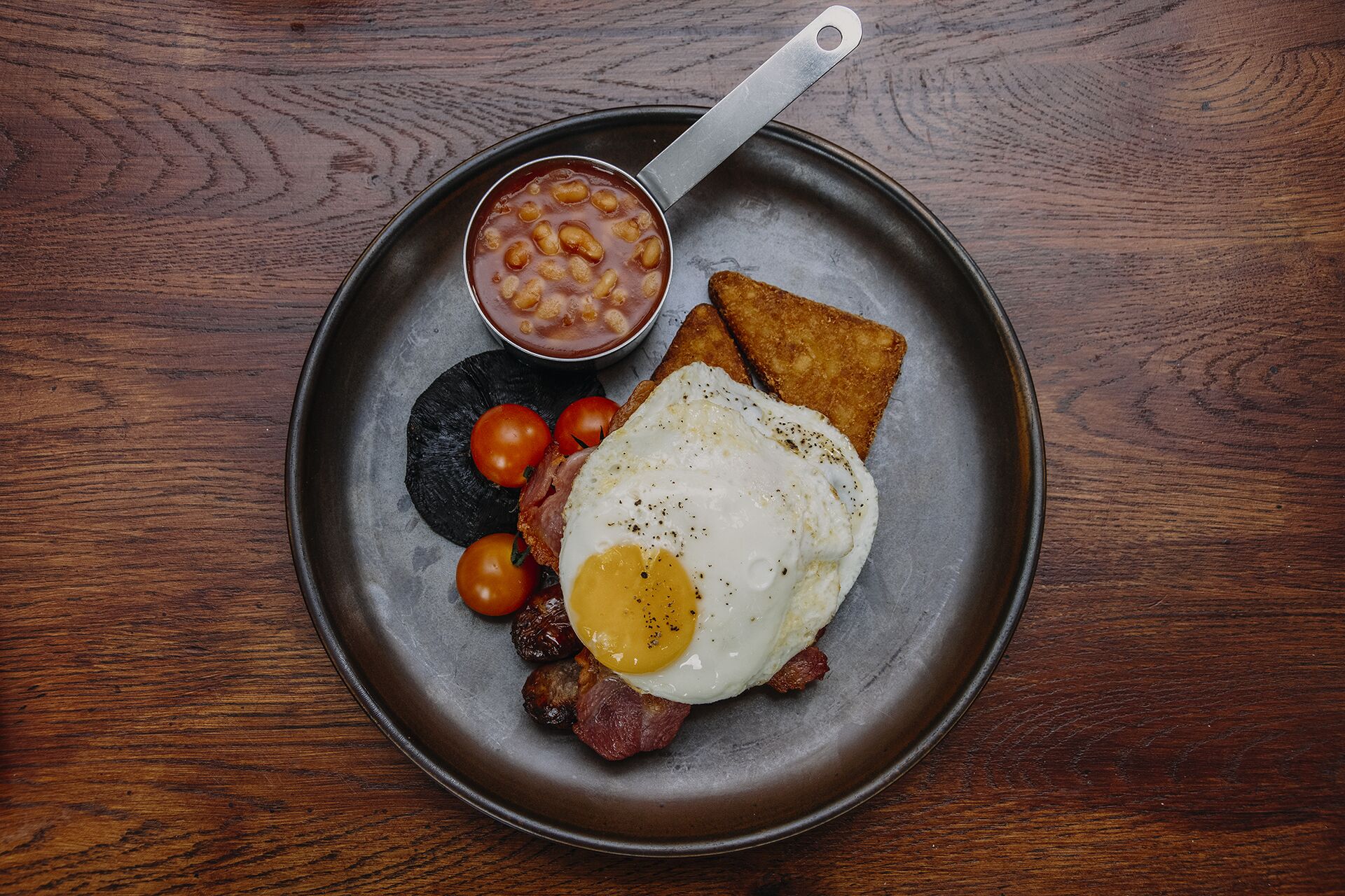 A breakfast plate with eggs, bacon, toast, tomatoes, and beans.
