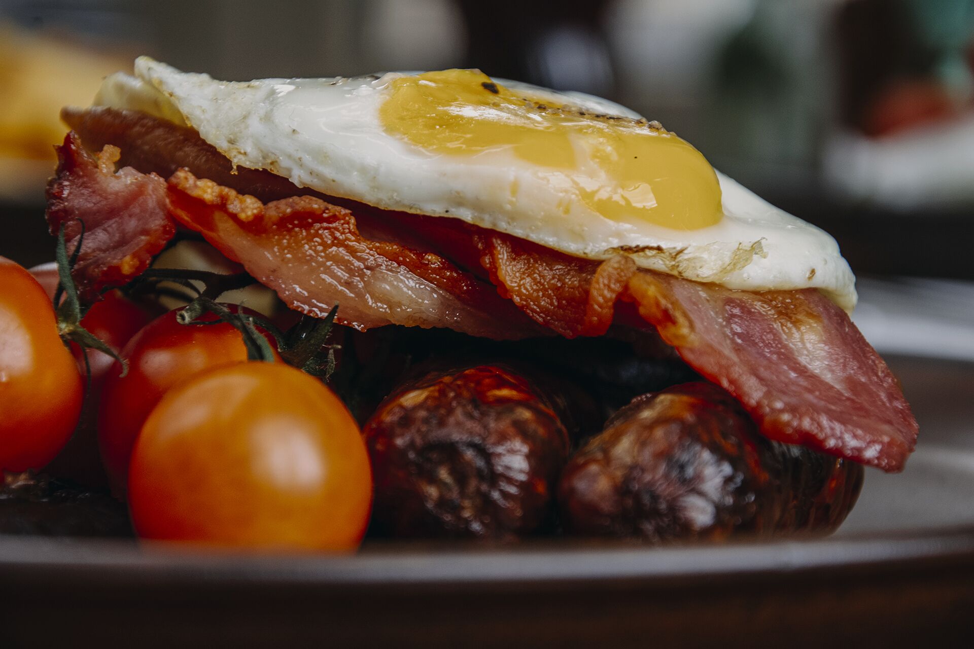 Une assiette de petit-déjeuner avec des œufs, du bacon, des saucisses et des tomates.