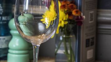 Una copa de vidrio transparente sobre una mesa de madera, con un florero de flores al fondo.