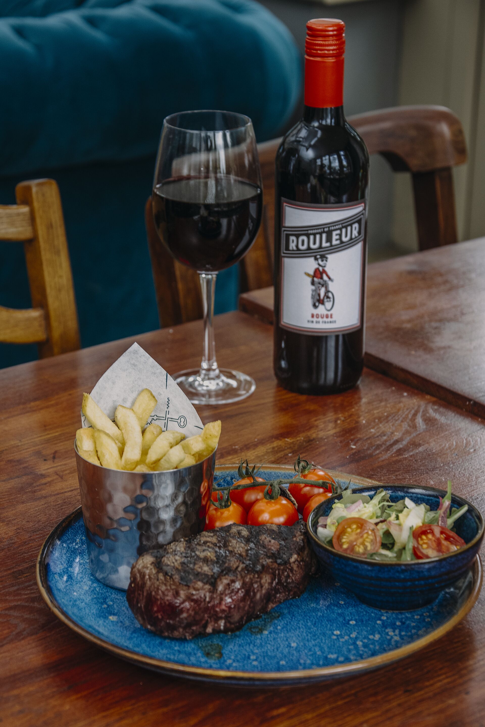 Une table à manger avec une assiette de nourriture, une bouteille de vin et un verre de vin.
