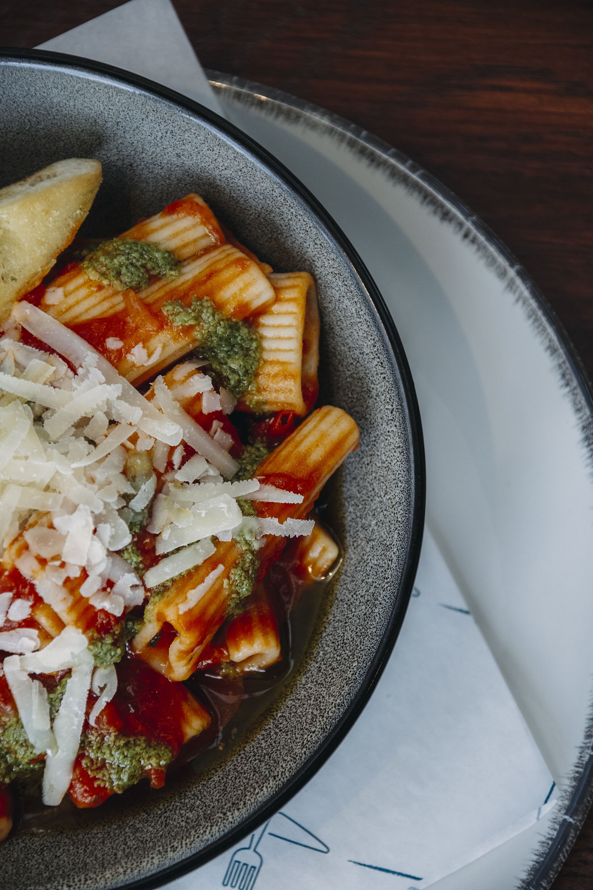 Un plato de pasta con pesto y queso rallado.