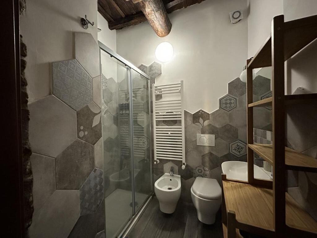 Un baño con cabina de ducha de vidrio, un bidé, un inodoro y un tocador de madera con espejo.