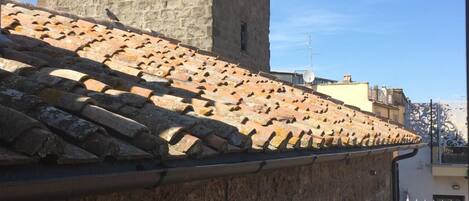 Un edificio de piedra con tejado de baldosas y una torre con varias ventanas.