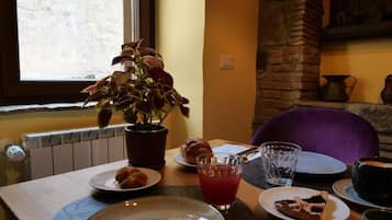 A dining table with plates, a glass of red beverage, a potted plant, and a croissant.