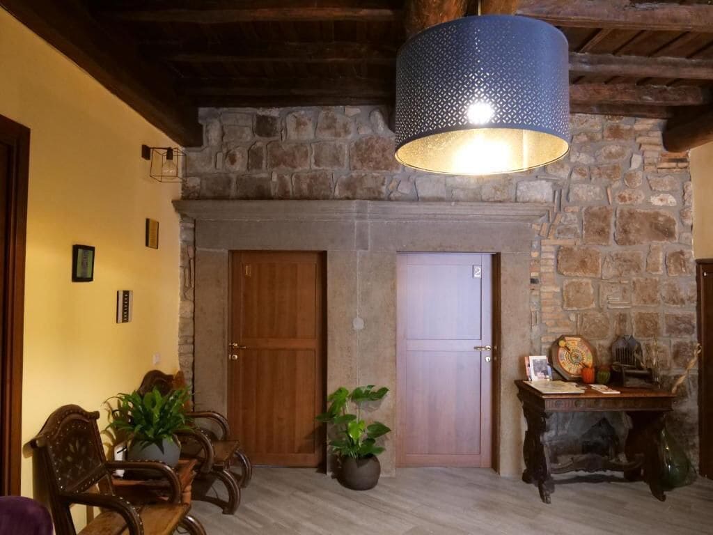 Un interior rústico con chimenea de piedra, puertas de madera y una lámpara colgante.