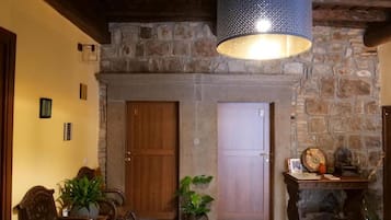 Un interior rústico con chimenea de piedra, puertas de madera y una lámpara colgante.