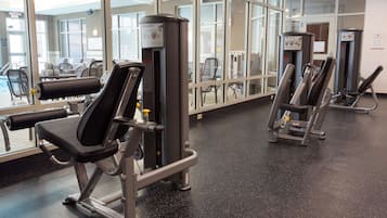 Une salle de sport équipée de machines d’exercice, dotée de grandes fenêtres et d’un sol à motifs.