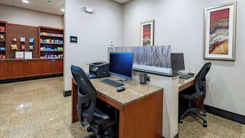 Zona de recepción de hotel con un mostrador que exhibe aperitivos y una estación de computadoras con dos sillas.