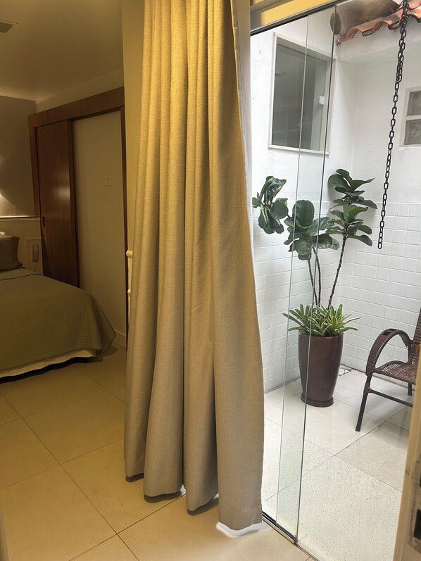 A room with a bed, a potted plant, and a chair. - Petit Village Icarai (Niteroi)