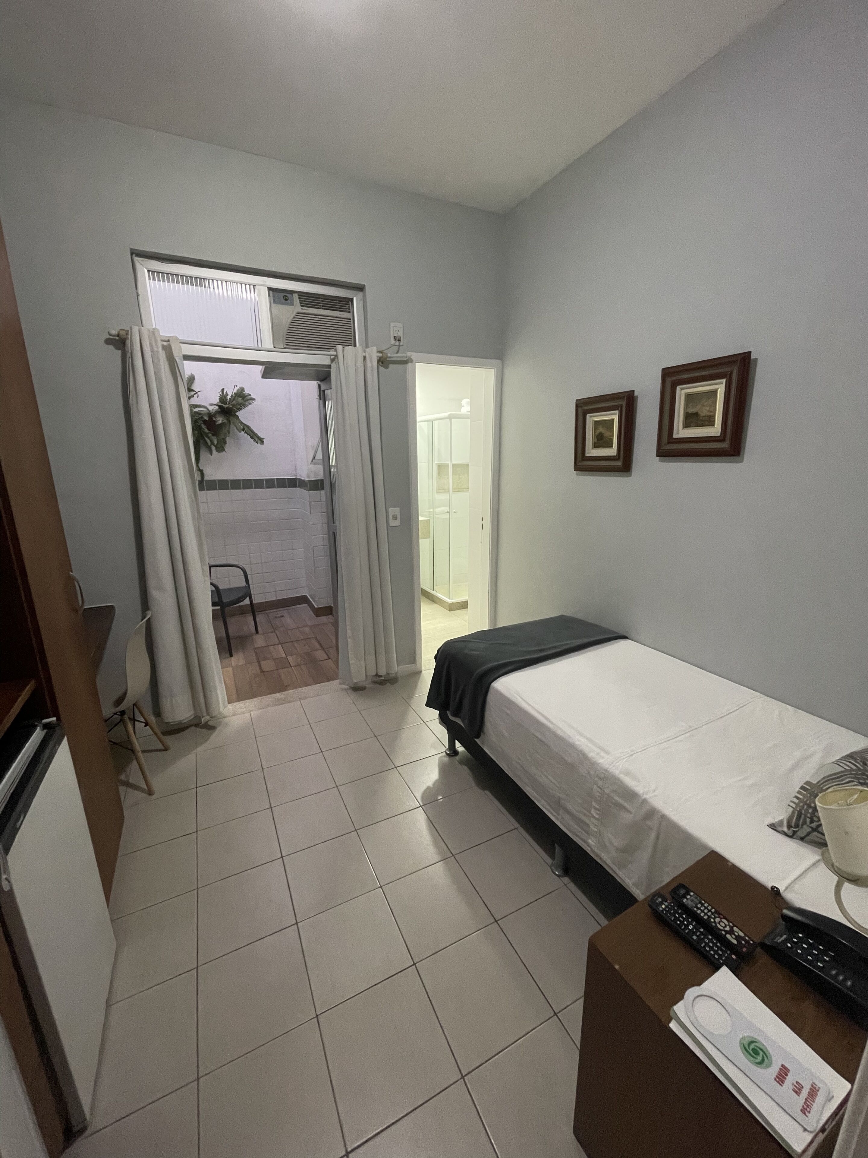 Een hotelkamer met een bed, een bureau met lamp, een stoel en een badkamer zichtbaar door een geopende deur.