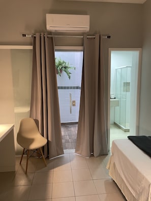 Habitación de hotel con cama, una silla, aire acondicionado y vistas al exterior.