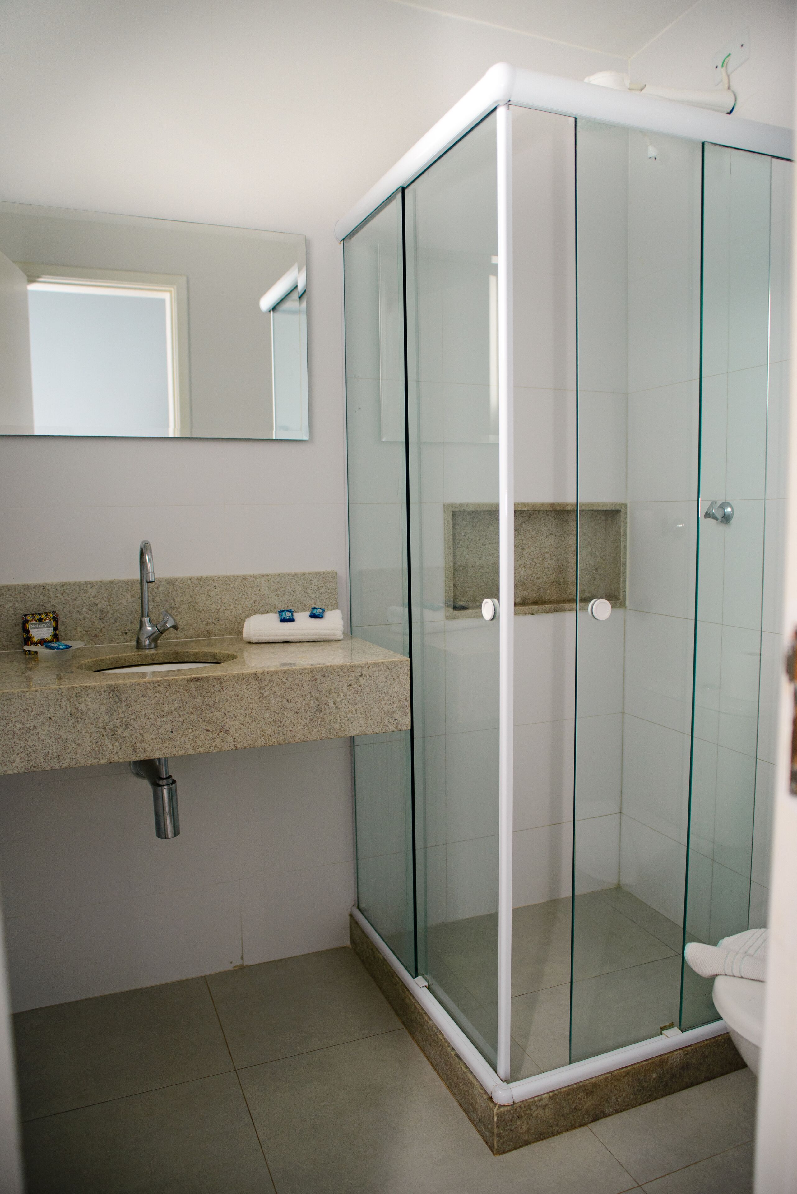 Une salle de bain avec une douche à parois de verre, un lavabo avec un miroir au-dessus et des toilettes.