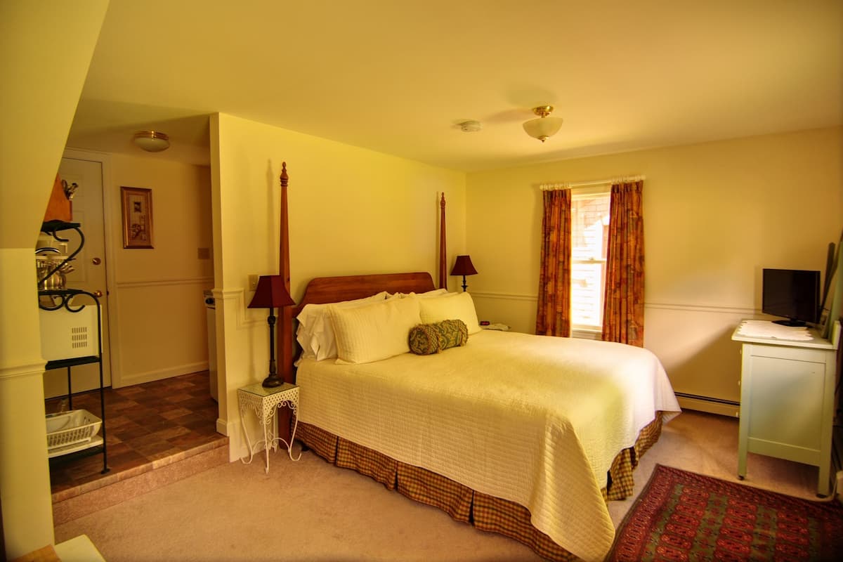 A neatly arranged bedroom with a bed, bedside tables, a lamp, a television, and a window with curtains.