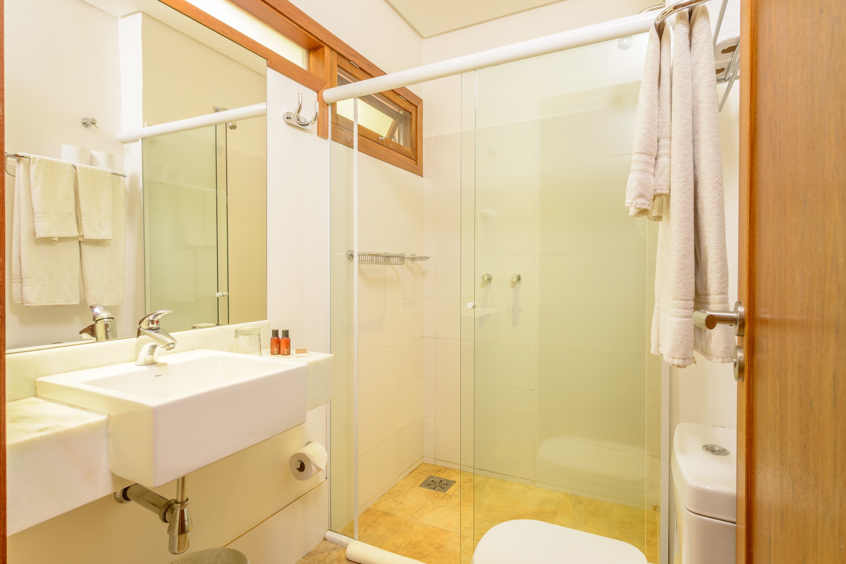 A modern bathroom with a glass-enclosed shower, a white sink, and a toilet.