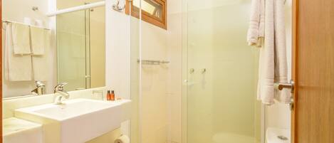 A modern bathroom with a glass-enclosed shower, a white sink, and a toilet.