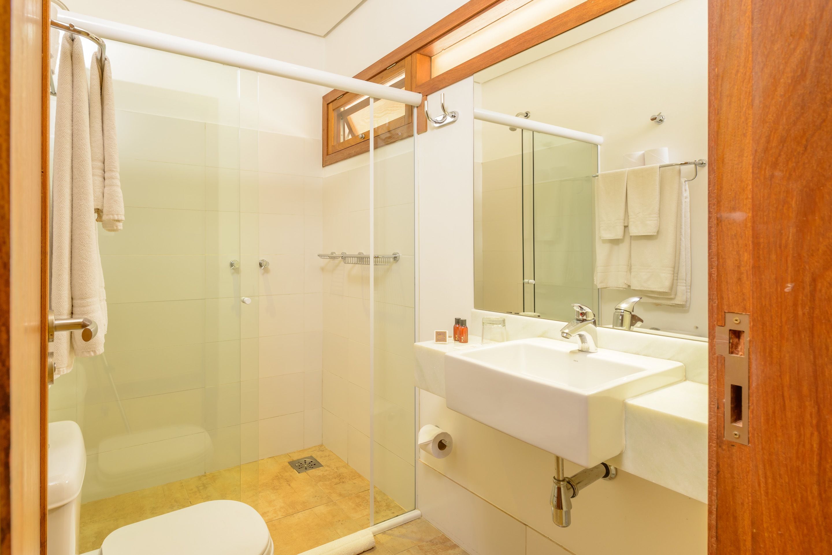 A bathroom with a glass-enclosed shower, a white sink, and a toilet.