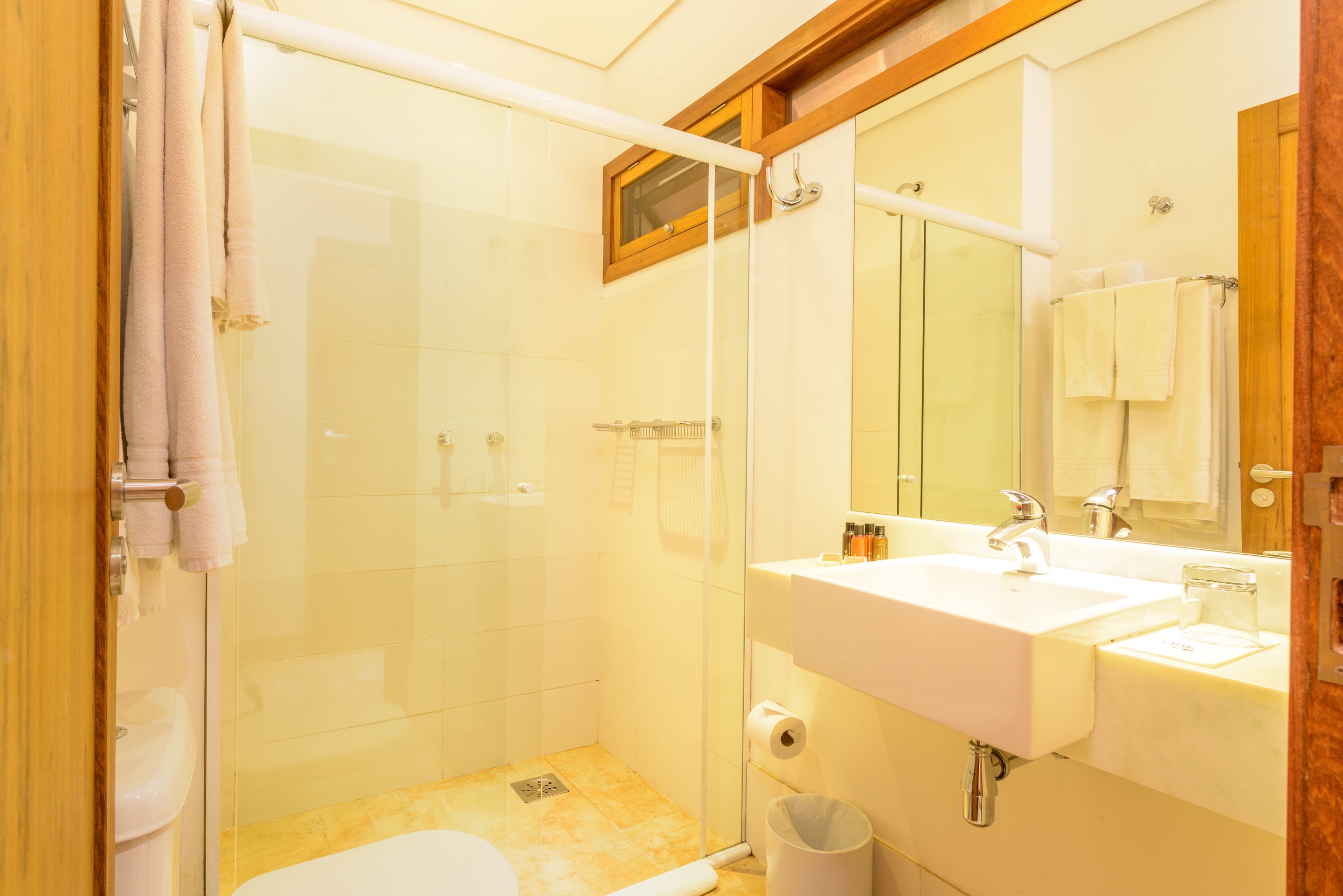 Een badkamer met een douchecabine van glas, een witte wastafel en een spiegel boven de wastafel.