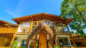 Un bâtiment moderne doté d’une façade en bois, de grandes fenêtres et d’une structure de toit en chaume.