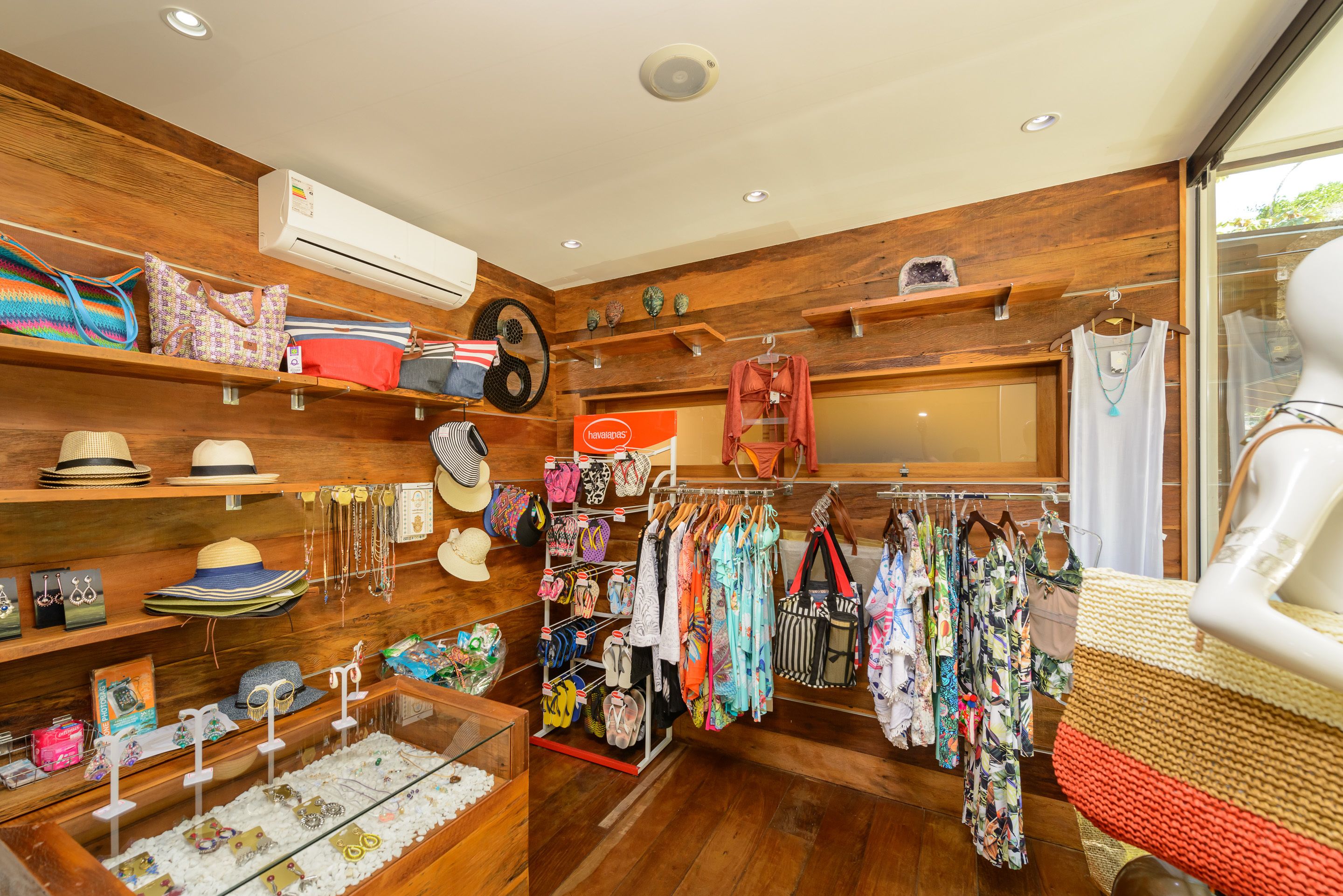 Una tienda boutique con estantes de madera que exhiben sombreros, bolsos y ropa.