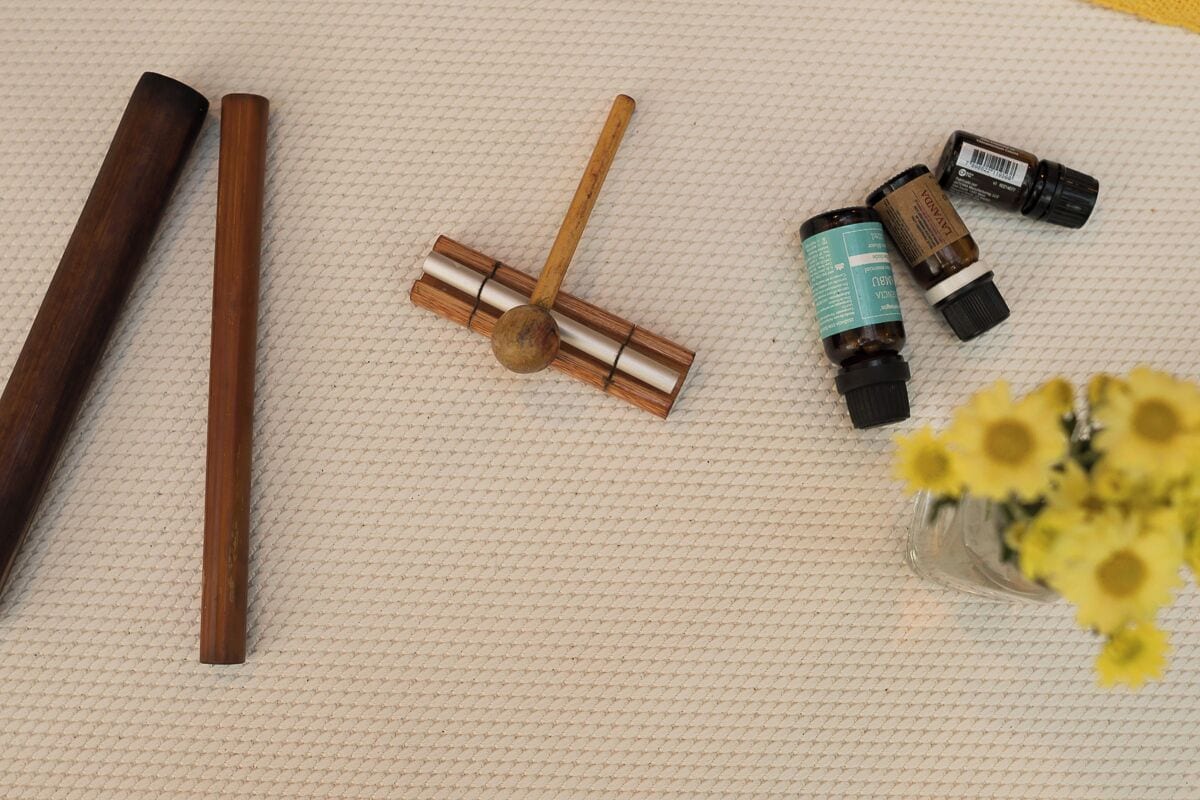 Un objet en bois, un petit outil en bois et trois petites bouteilles sur une surface texturée.