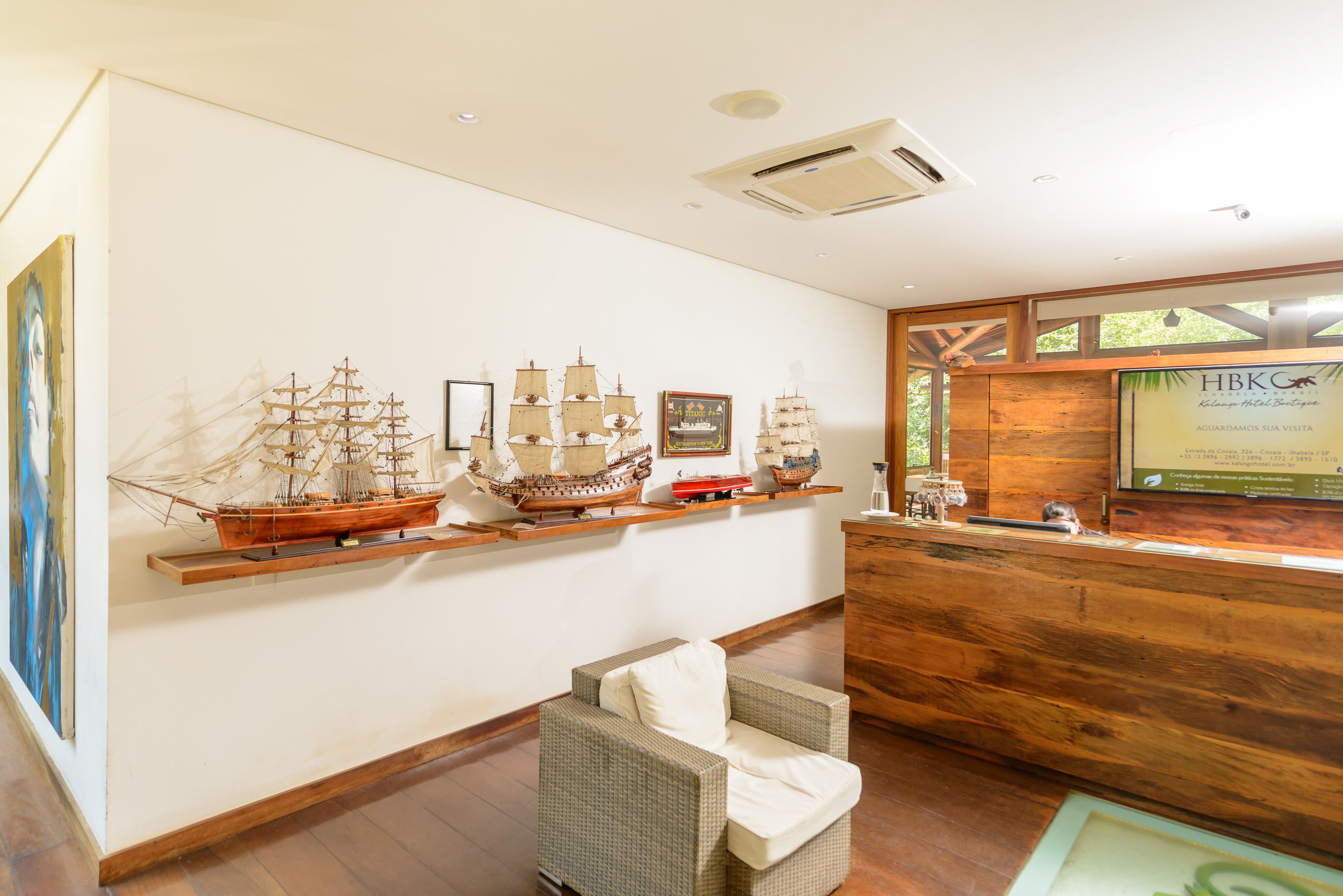 Uma área de recepção com painéis de madeira, um balcão e uma exposição de modelos de navios em prateleiras.