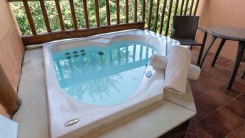 Un jacuzzi sur un balcon doté d’une rambarde en bois, d’une chaise et d’une petite table.