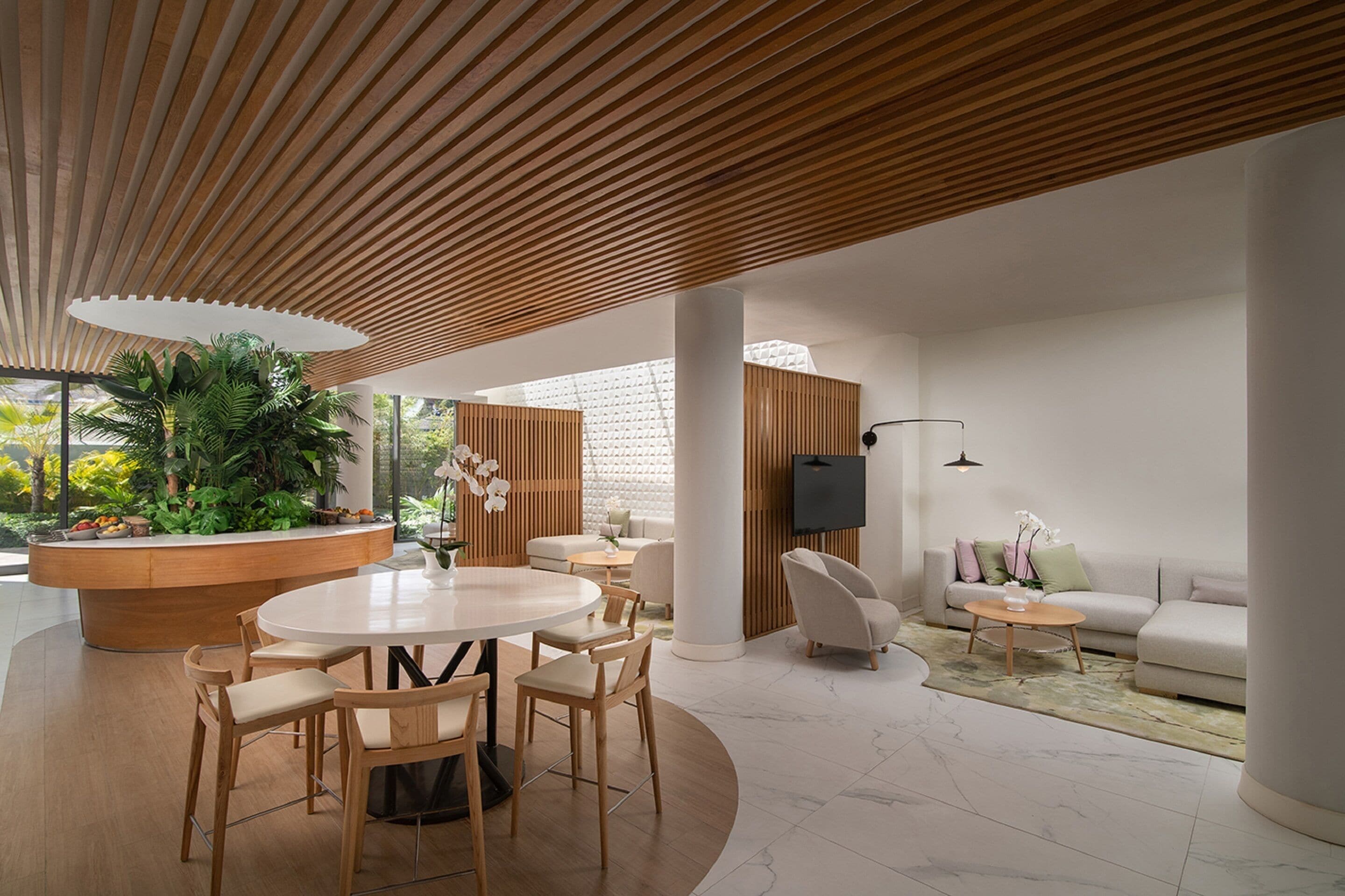 Een modern interieur met een ronde eettafel, houten stoelen, een bank en een televisie.
