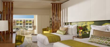 A hotel room with two beds, a desk, a chair, and a balcony with a view of buildings.