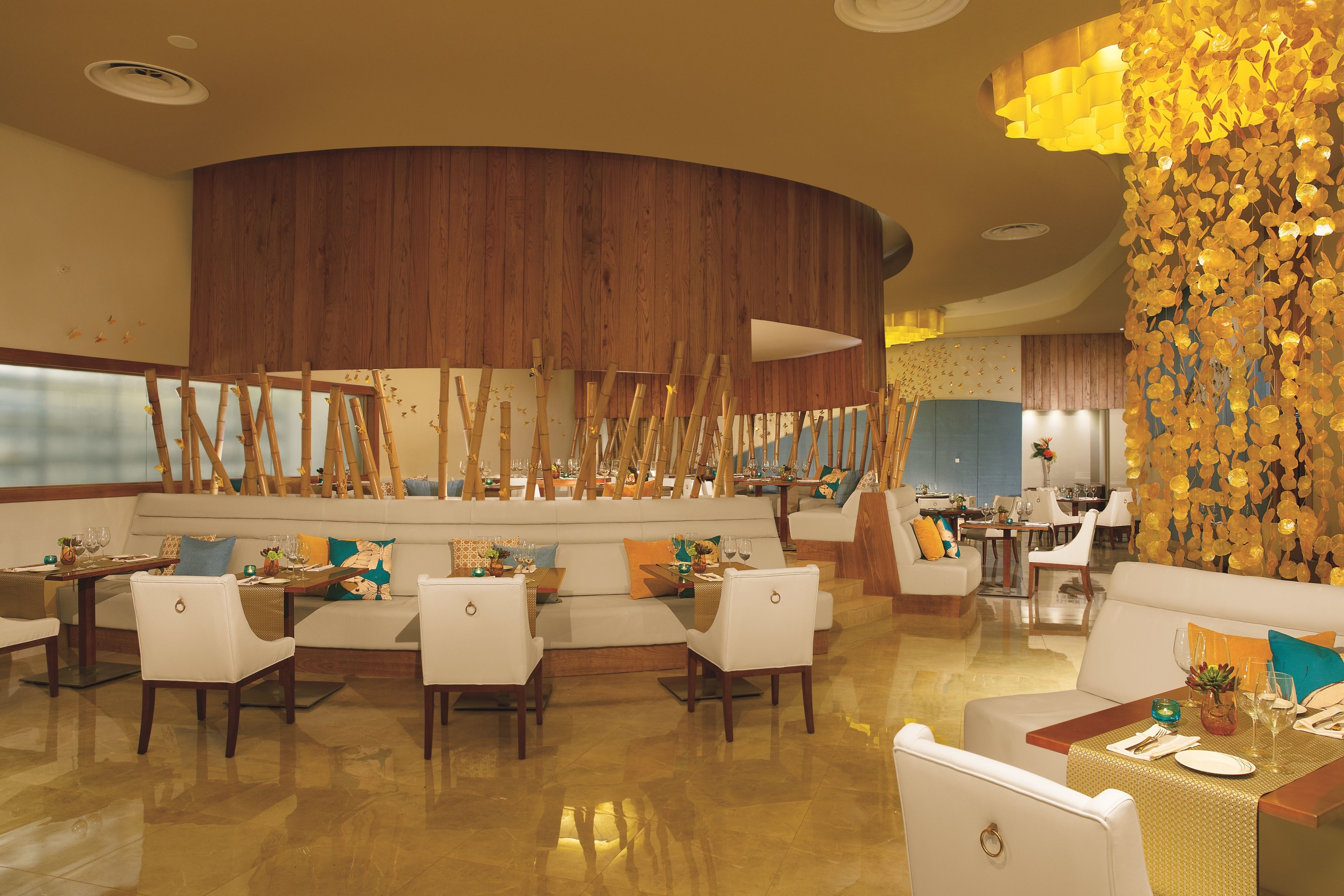 A restaurant with a wooden accent wall, white furniture, and a decorative golden wall feature.