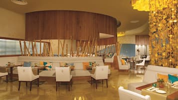 A restaurant with a wooden accent wall, white furniture, and a decorative golden wall feature.