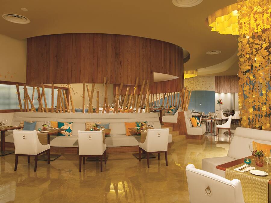 A restaurant with a wooden accent wall, white furniture, and a decorative golden wall feature.