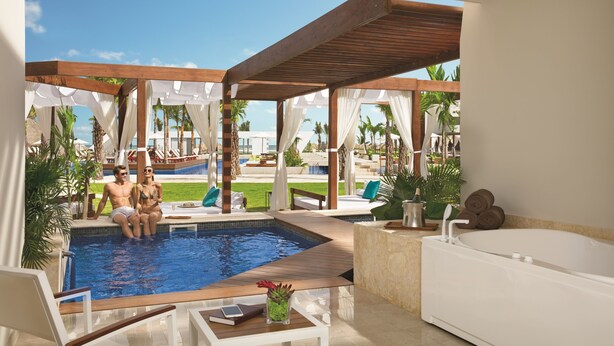 Un espace piscine doté d’une terrasse en bois, d’un jacuzzi et offrant une vue sur la piscine.