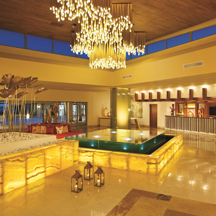 A spacious lobby with a central pool, a modern chandelier, and a seating area.