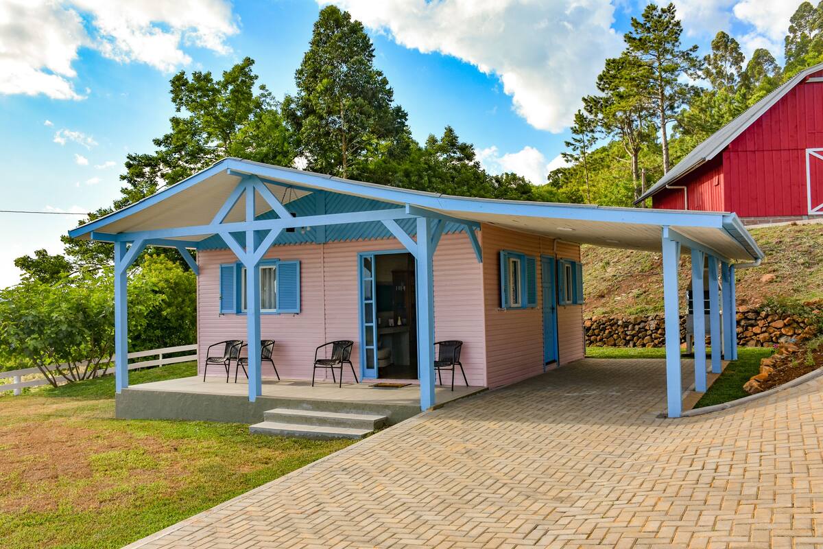 A pink and blue cabin with a covered porch and two chairs.