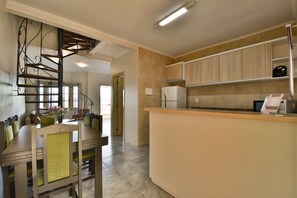 Uma cozinha moderna com uma ilha central, armários de madeira e uma escada em espiral.