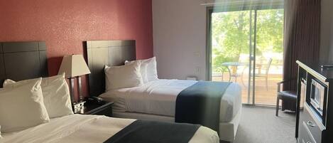 A hotel room with two beds, a desk, and a television.