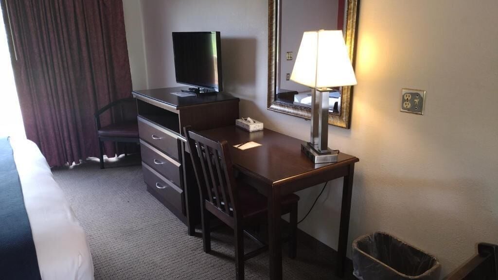 Une chambre d’hôtel équipée d’un bureau, d’une chaise, d’une télévision, d’une lampe et d’une poubelle.