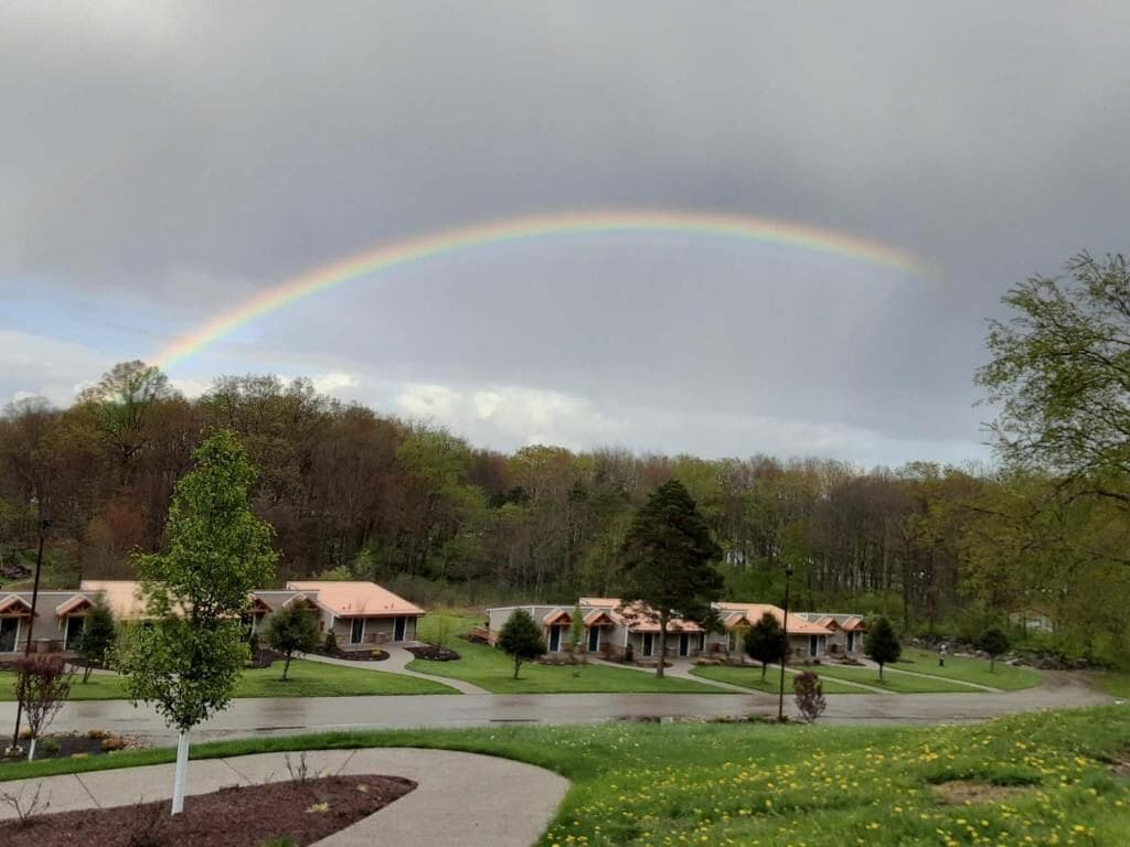 A residential area with a row of houses, a curved driveway, and a rainbow in the sky.