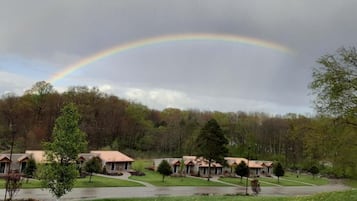A residential area with a row of houses, a curved driveway, and a rainbow in the sky.