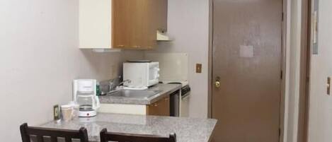 A compact kitchen with a dining area, a microwave, and a coffee maker.