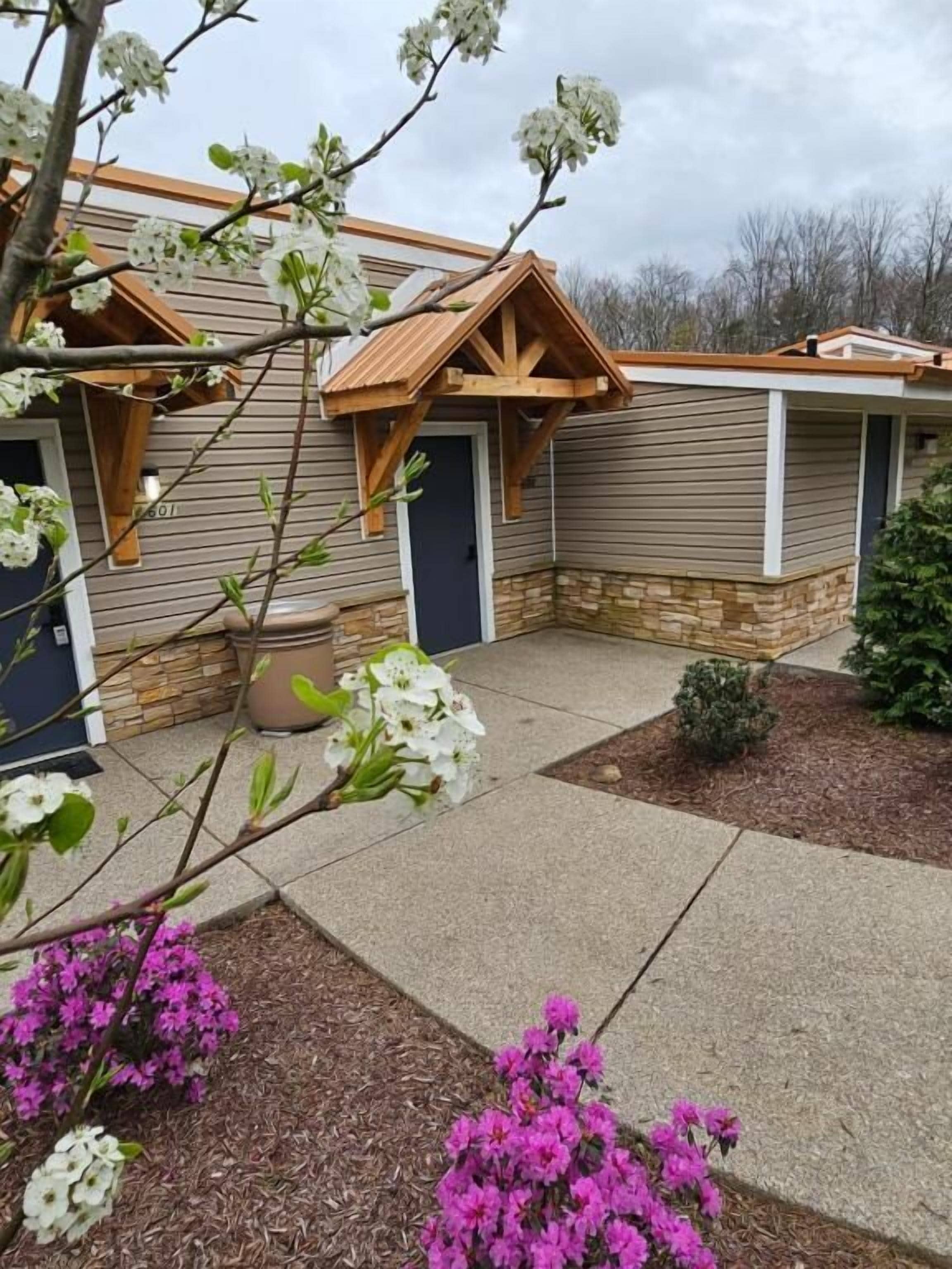 A residential building with a covered porch, a potted plant, and a landscaped garden area.
