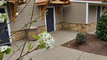 A residential building with a covered porch, a potted plant, and a landscaped garden area.