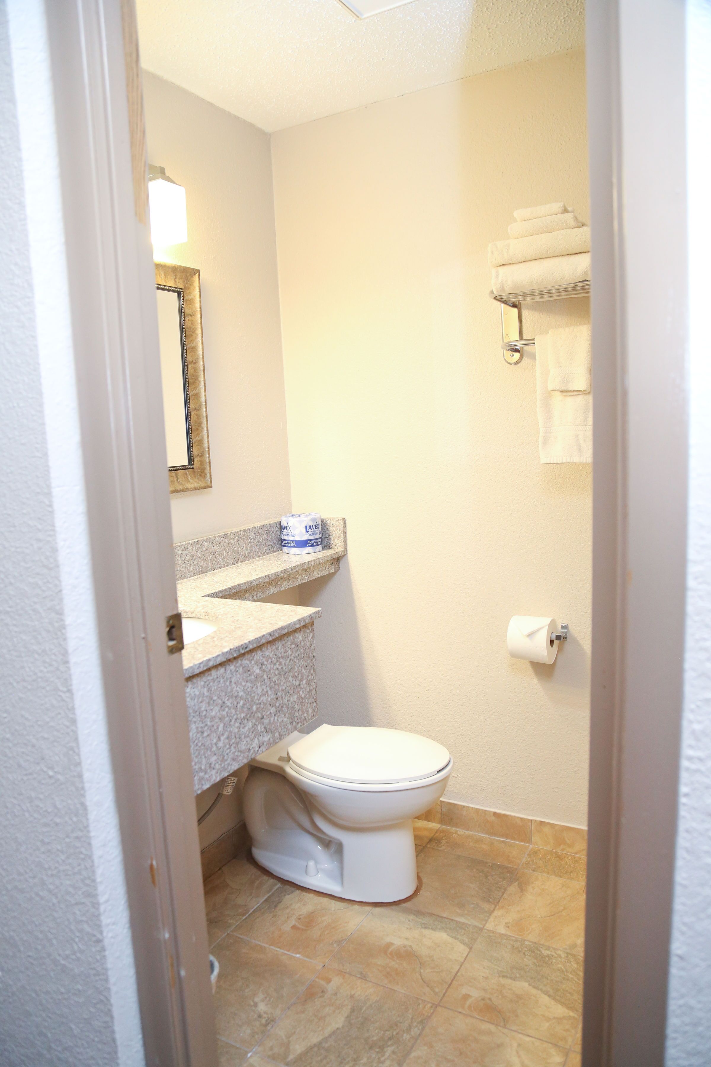 Een kleine, schone badkamer met toilet, wastafel en handdoekhouder.