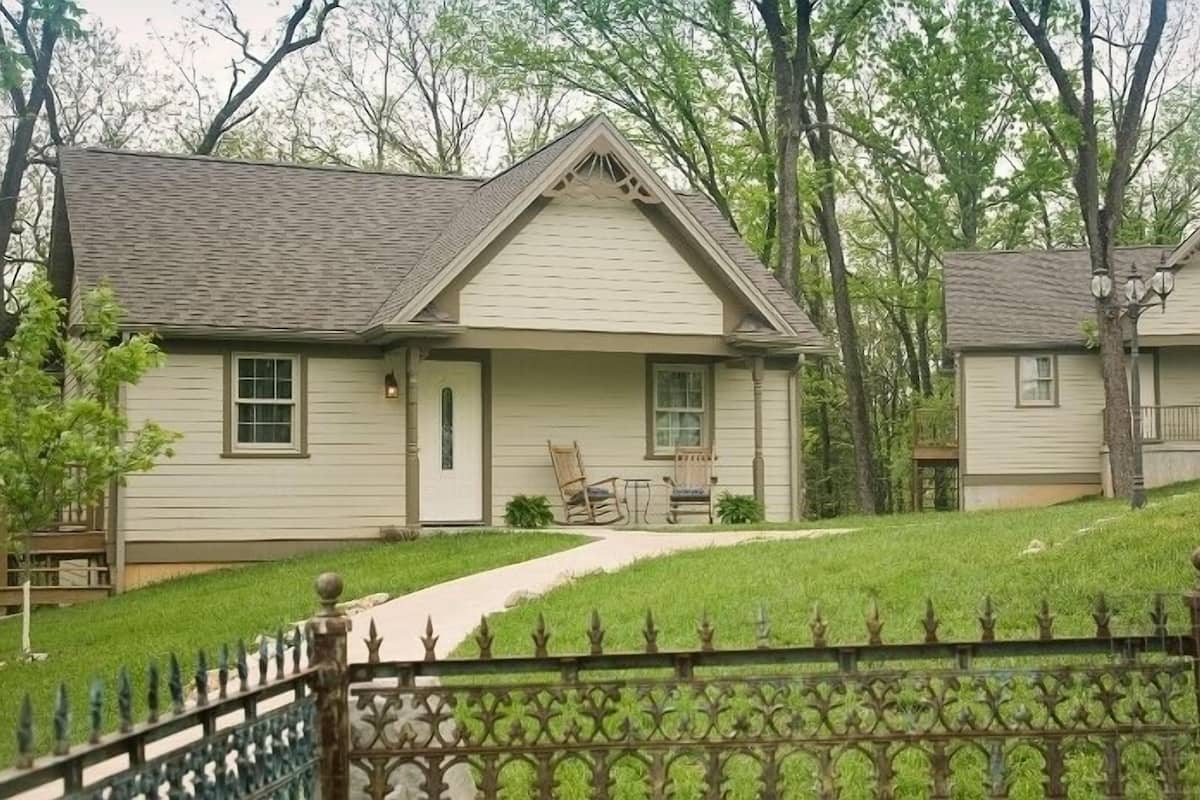 A two-story house with a front porch, a small deck, and a fenced yard.