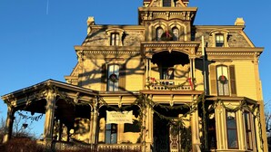 A large, ornate mansion with a prominent entrance, a balcony with festive decorations, and a sign indicating it is a bed and breakfast.